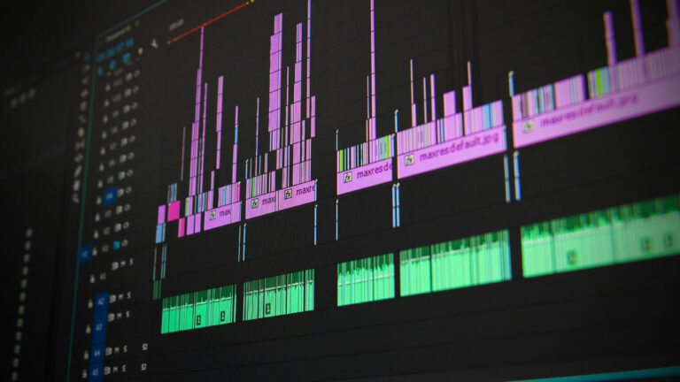 Close-up of a video editing software interface displaying a timeline with multiple audio and video tracks, represented by various colored waveforms and clips.