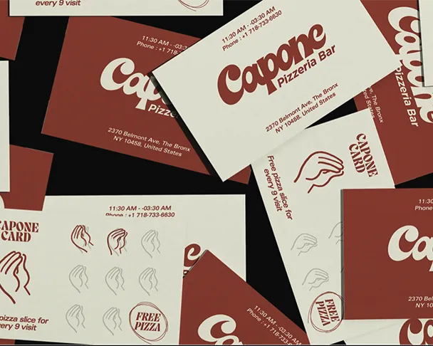 Business cards and promotional materials featuring "Capone Pizzeria Bar" and a hand logo are scattered. Text includes address: "2370 Belmont Ave, The Bronx, NY 10458, United States," and "FREE PIZZA, Pizza slice for every 9 visit," with hours and phone number "11:30 AM - 03:30 AM, Phone: +1 718-733-6630."