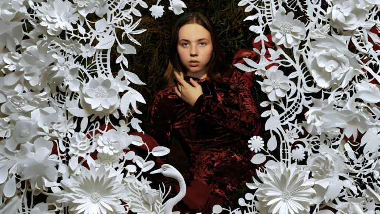 Image of woman dressed in red framed by paper cutout flowers