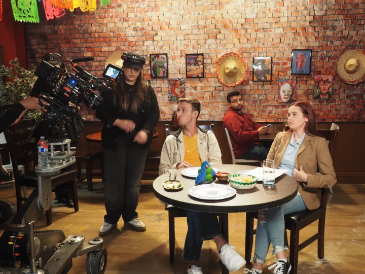 Students acting on a movie set setup like a restaurant or cafe