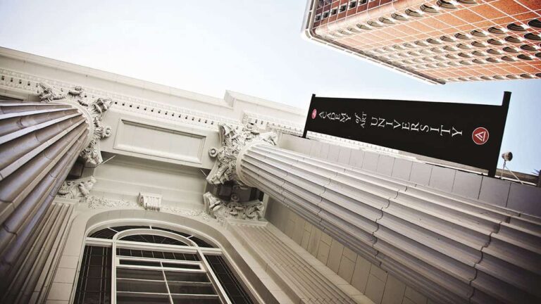 Columns frame a classic building facade with ornate details; a sign reads 